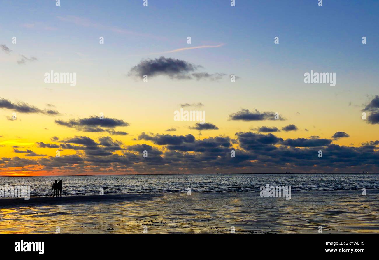 Vue sur le soleil couchant qui brille sur la mer et se reflète sur la plage, nuages avec des bords ensoleillés.Paysage Banque D'Images