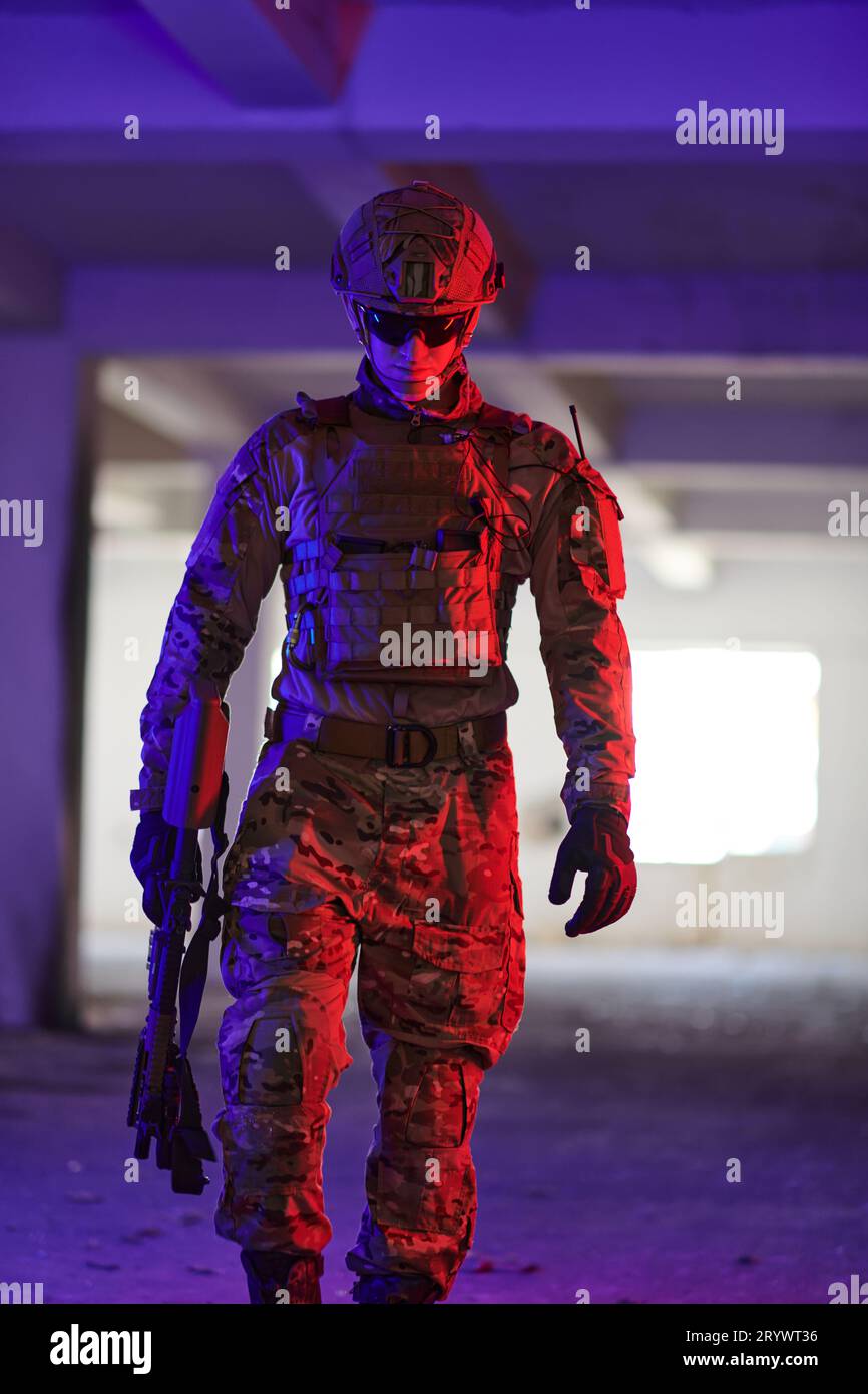 Un soldat professionnel entreprend une mission périlleuse dans un bâtiment abandonné éclairé par des néons bleus et violets Banque D'Images