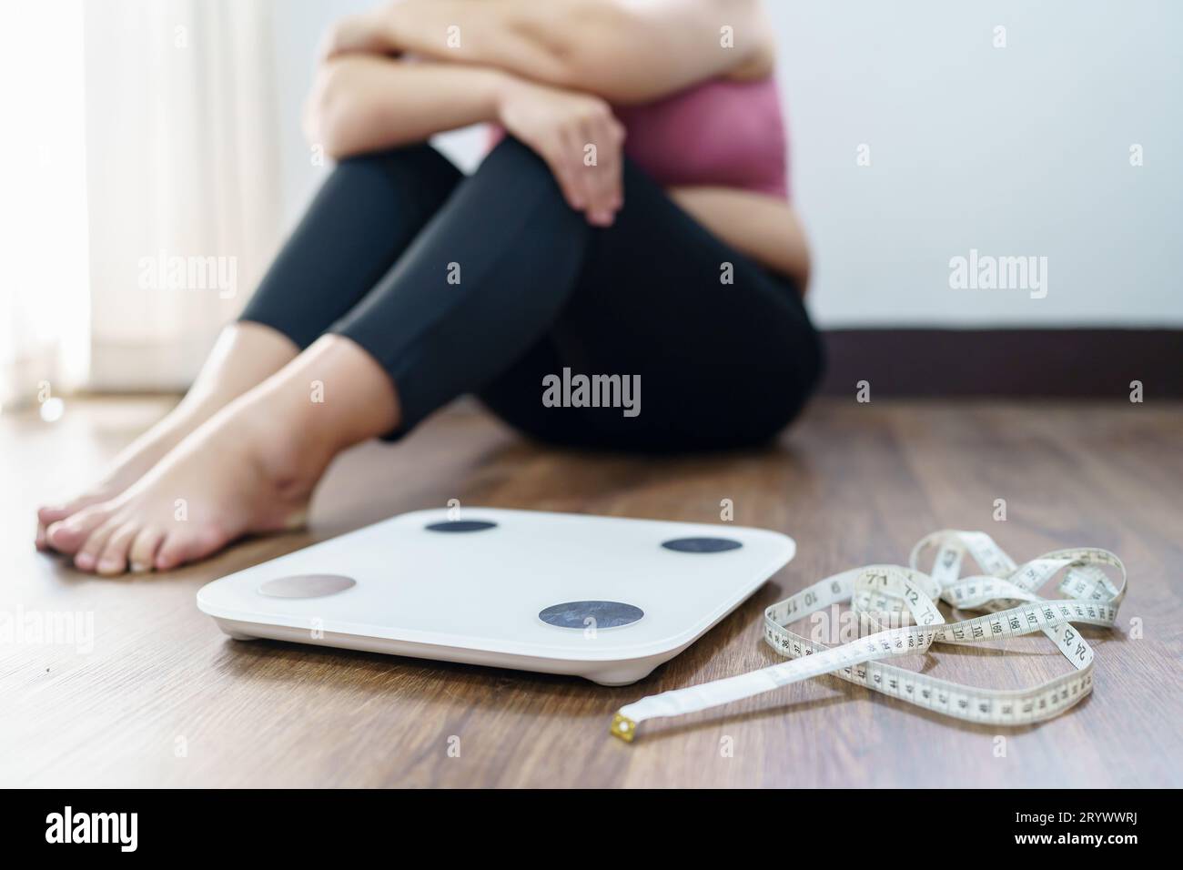 Femme obèse avec bouleversement de graisse ennuyé de suivre un régime perte de poids failÂ régime gras et échelle triste femme asiatique sur l'échelle de poids au poids à la maison Banque D'Images