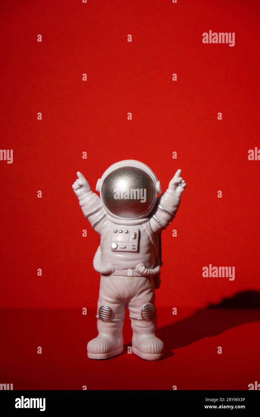 Astronaute jouet en plastique sur fond rouge coloré Copier l'espace. Concept de voyage hors de la terre, vols commerciaux privés d'homme spatial Banque D'Images