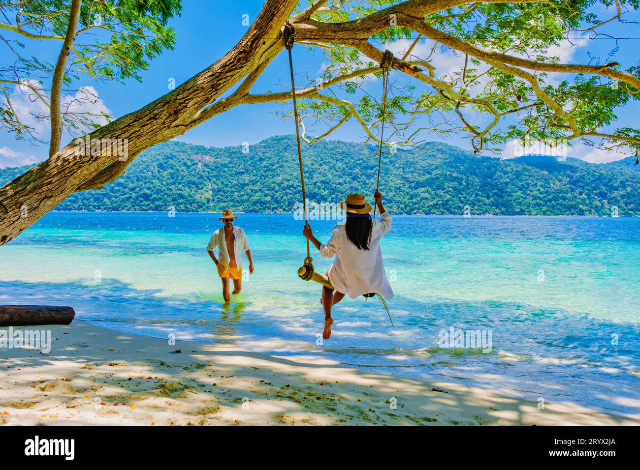 Un couple d'hommes et de femmes sont sur la plage avec une balançoire à corde Banque D'Images