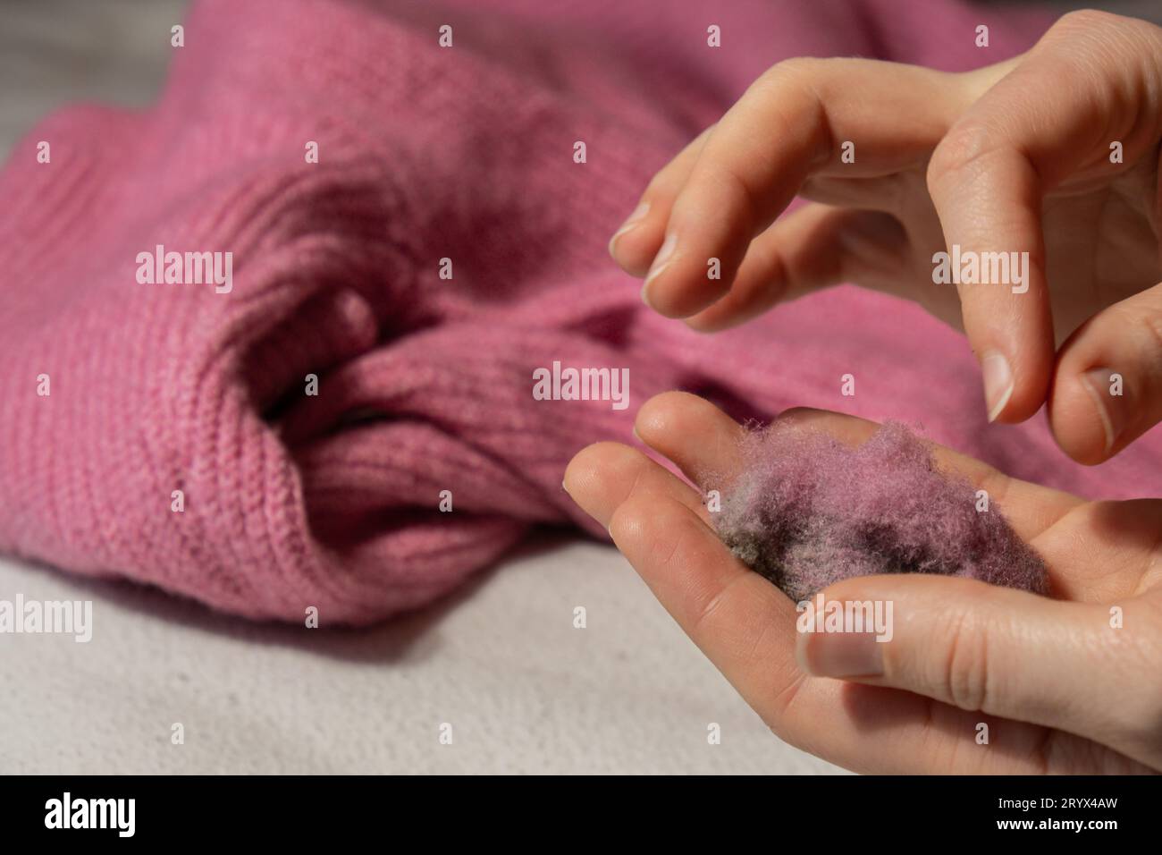 Femme utilisant le rasoir anti-boulochage à la maison. Dispositif pour raser des vêtements. Rasoir à tissu anti-peluche. Détartrant de peluches pour chandail portable électrique Banque D'Images