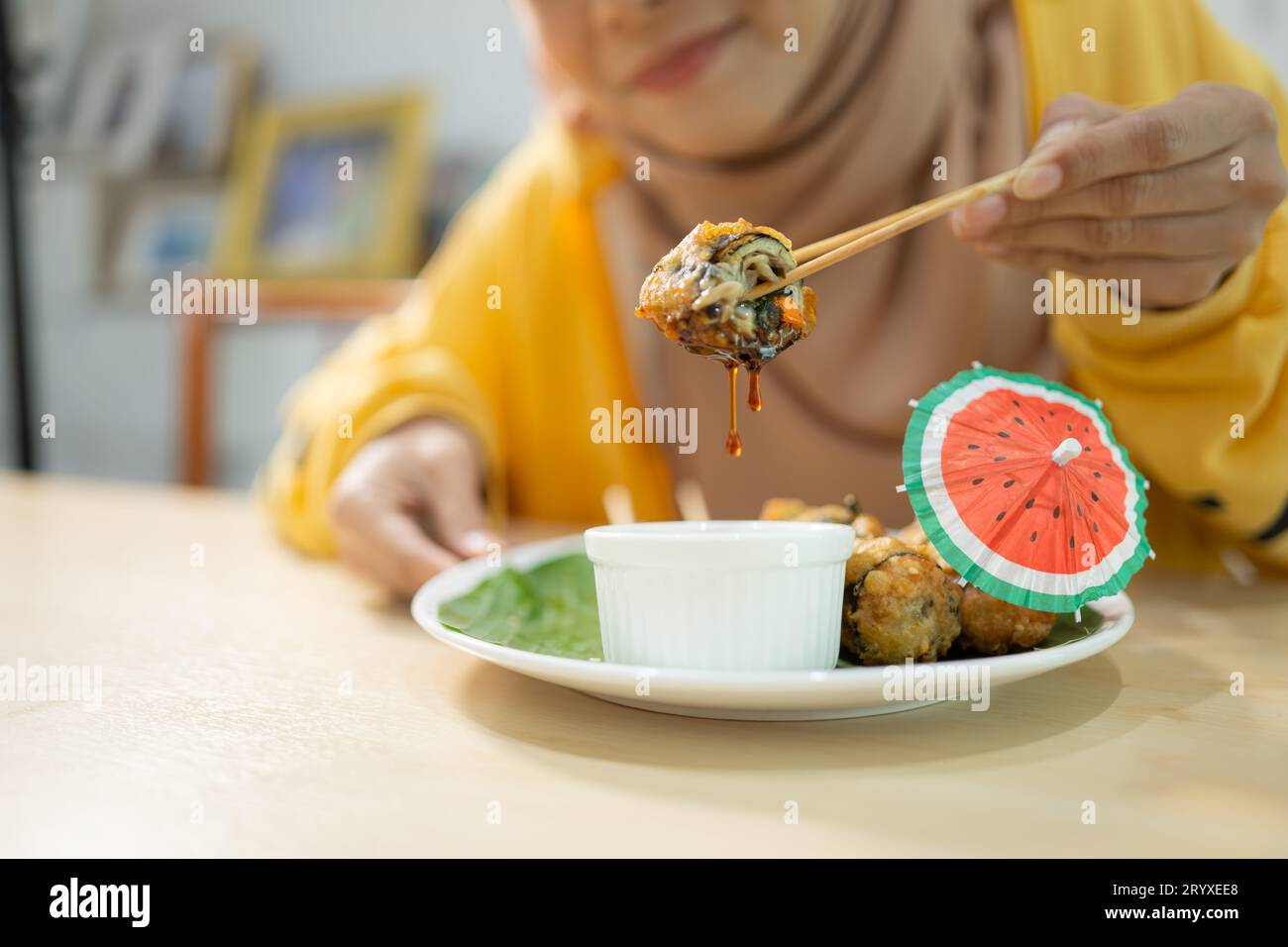 Fille musulmane mangeant des sushis aux champignons au restaurant. Focalisation sélective sur les sushis Banque D'Images