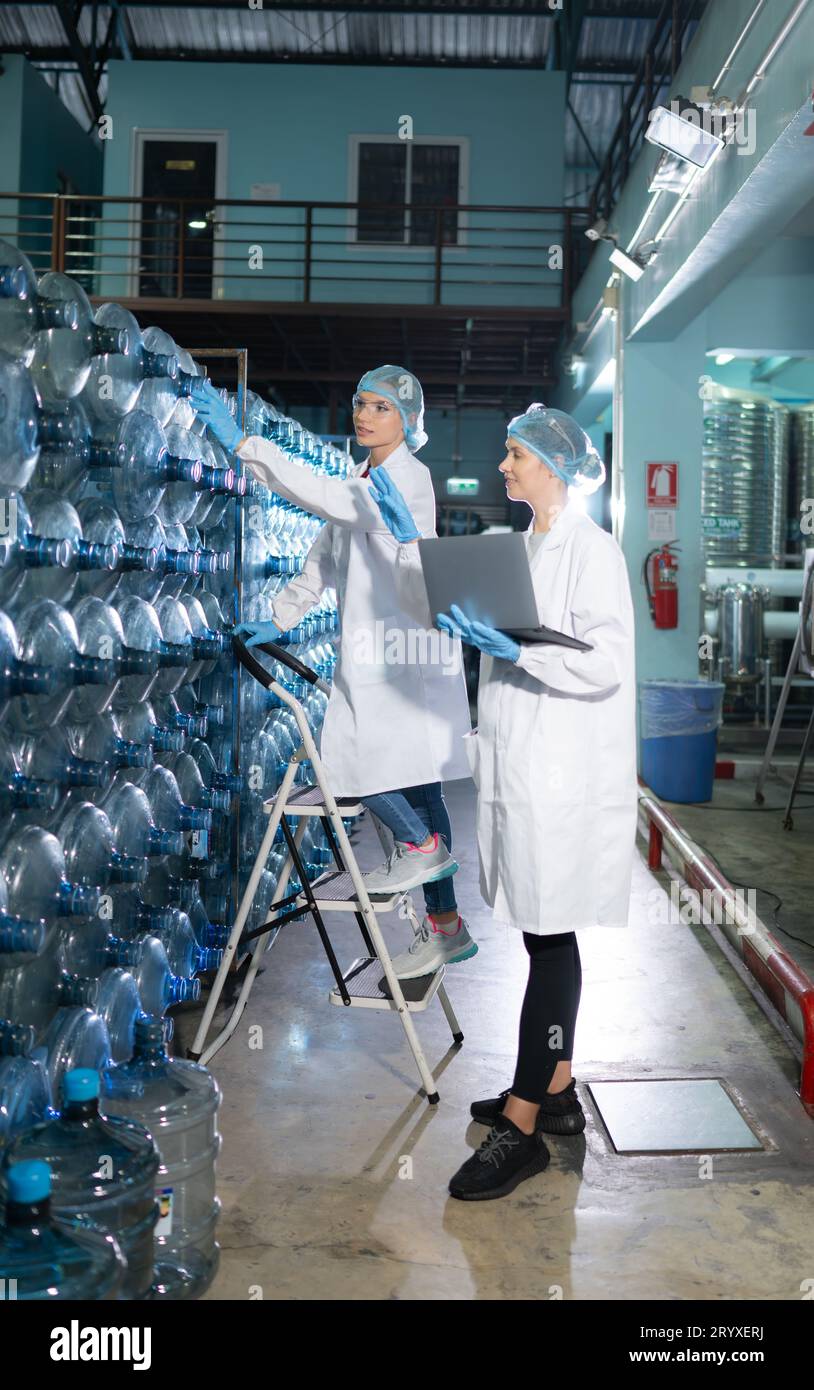 Portrait d'un scientifique dans l'usine d'eau potable utilisant une échelle, regardant les réservoirs d'eau au-dessus et examinant avec un coll. Banque D'Images