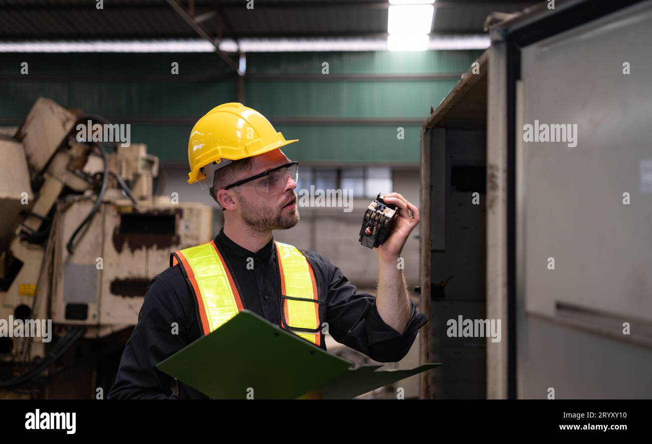 L'ingénieur inspecte le système électrique et répare le système mécanique dans l'armoire de commande de la machine. pour le m Banque D'Images