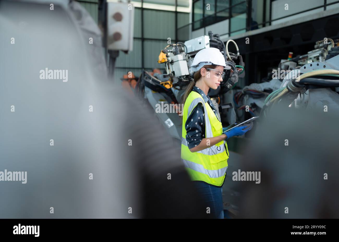 Une ingénieure installe un programme sur un bras robotique dans un entrepôt de robots. Et tester l'opération avant d'envoyer la machine t Banque D'Images