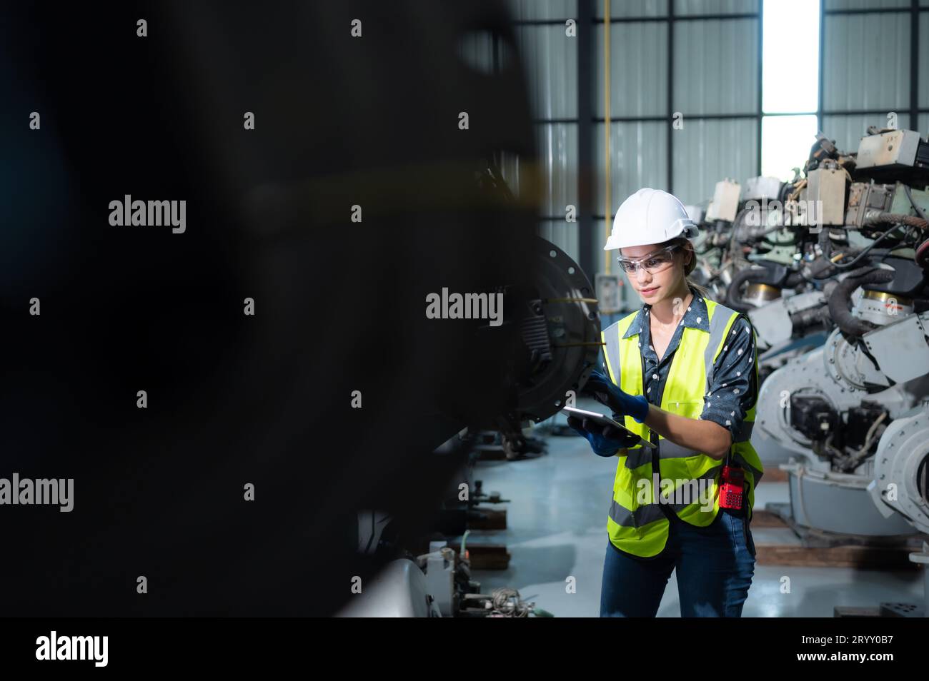 Une ingénieure installe un programme sur un bras robotique dans un entrepôt de robots. Et tester l'opération avant d'envoyer la machine t Banque D'Images