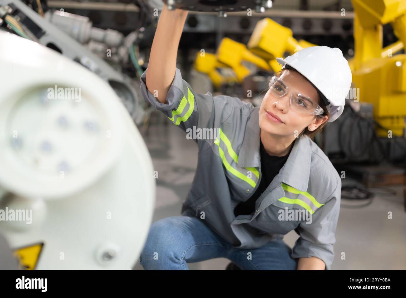 Une ingénieure installe un programme sur un bras robotique dans un entrepôt de robots. Et tester l'opération avant d'envoyer la machine t Banque D'Images