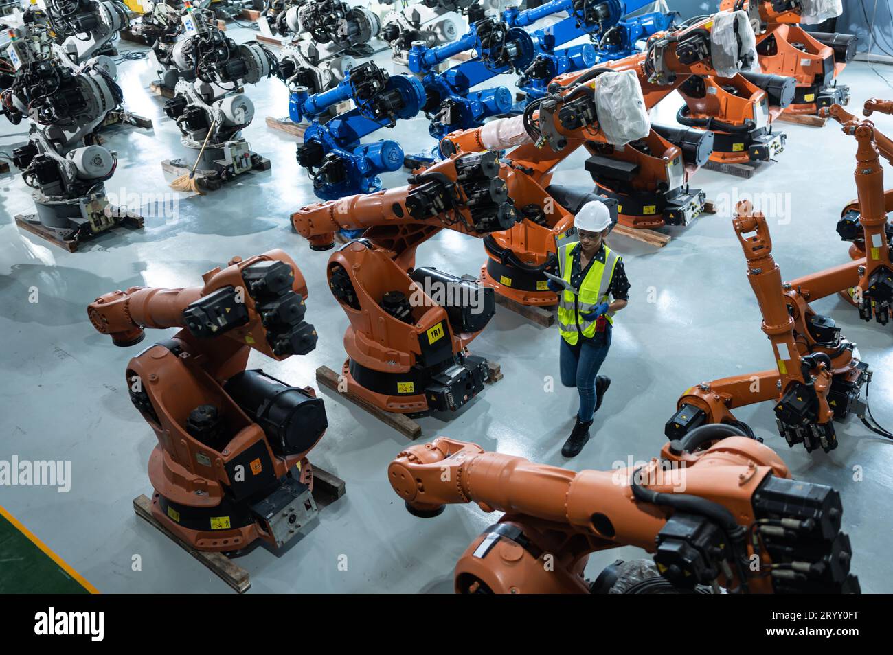 Une ingénieure installe un programme sur un bras robotique dans un entrepôt de robots. Et tester l'opération avant d'envoyer la machine t Banque D'Images