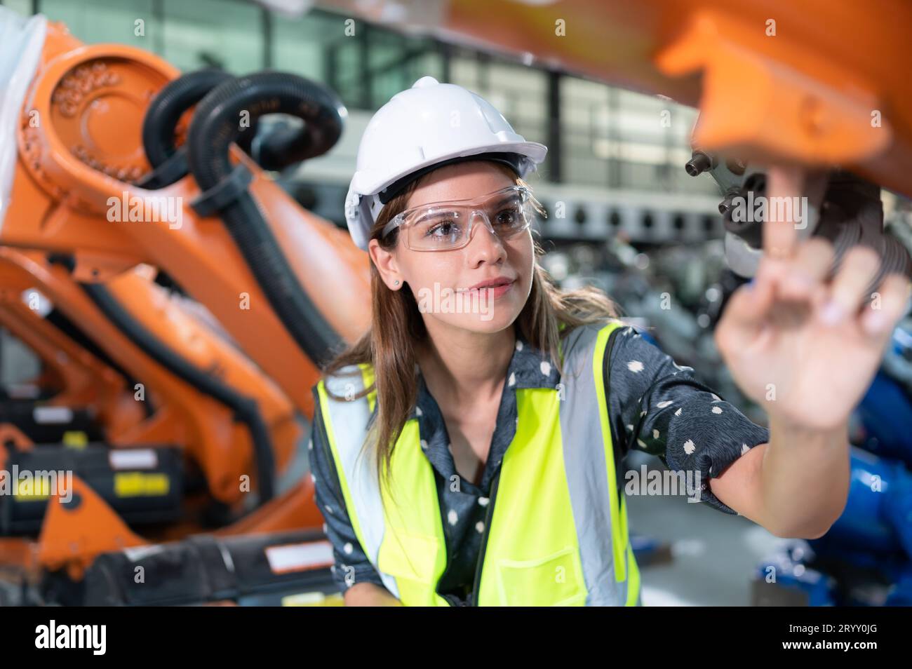 Une ingénieure installe un programme sur un bras robotique dans un entrepôt de robots. Et tester l'opération avant d'envoyer la machine t Banque D'Images