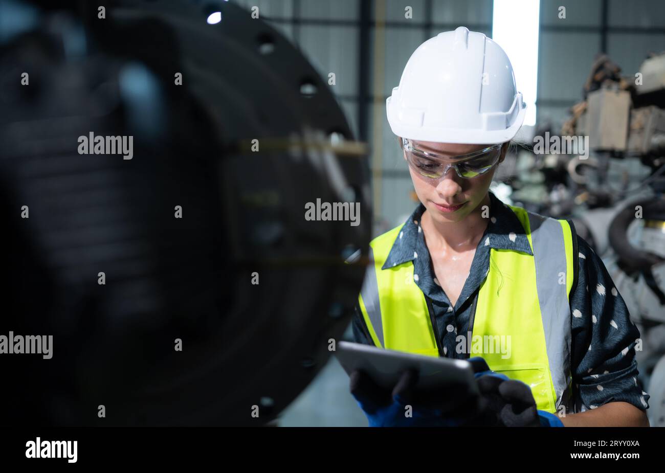 Une ingénieure installe un programme sur un bras robotique dans un entrepôt de robots. Et tester l'opération avant d'envoyer la machine t Banque D'Images