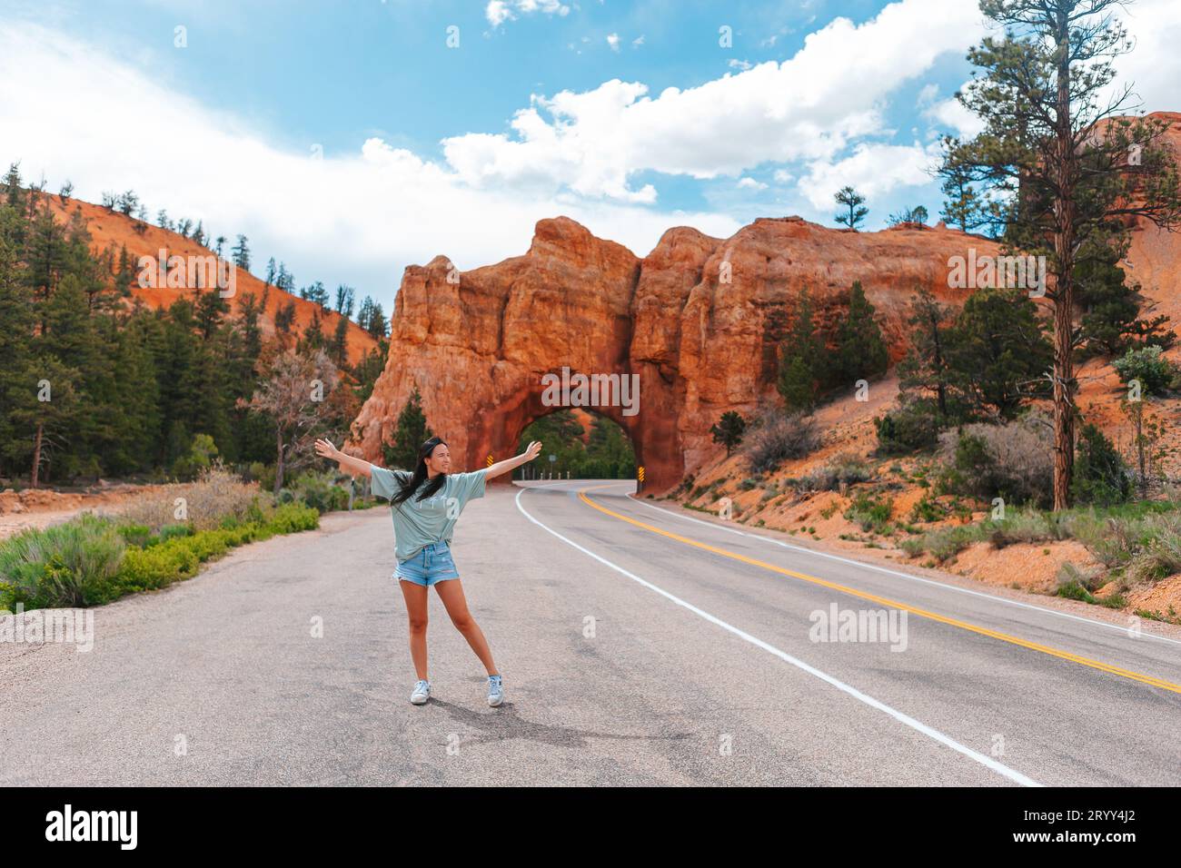 Jeune femme heureuse en arrière-plan de pont arc en pierre naturelle dans le parc national de Red Canyon dans l'Utah, États-Unis Banque D'Images