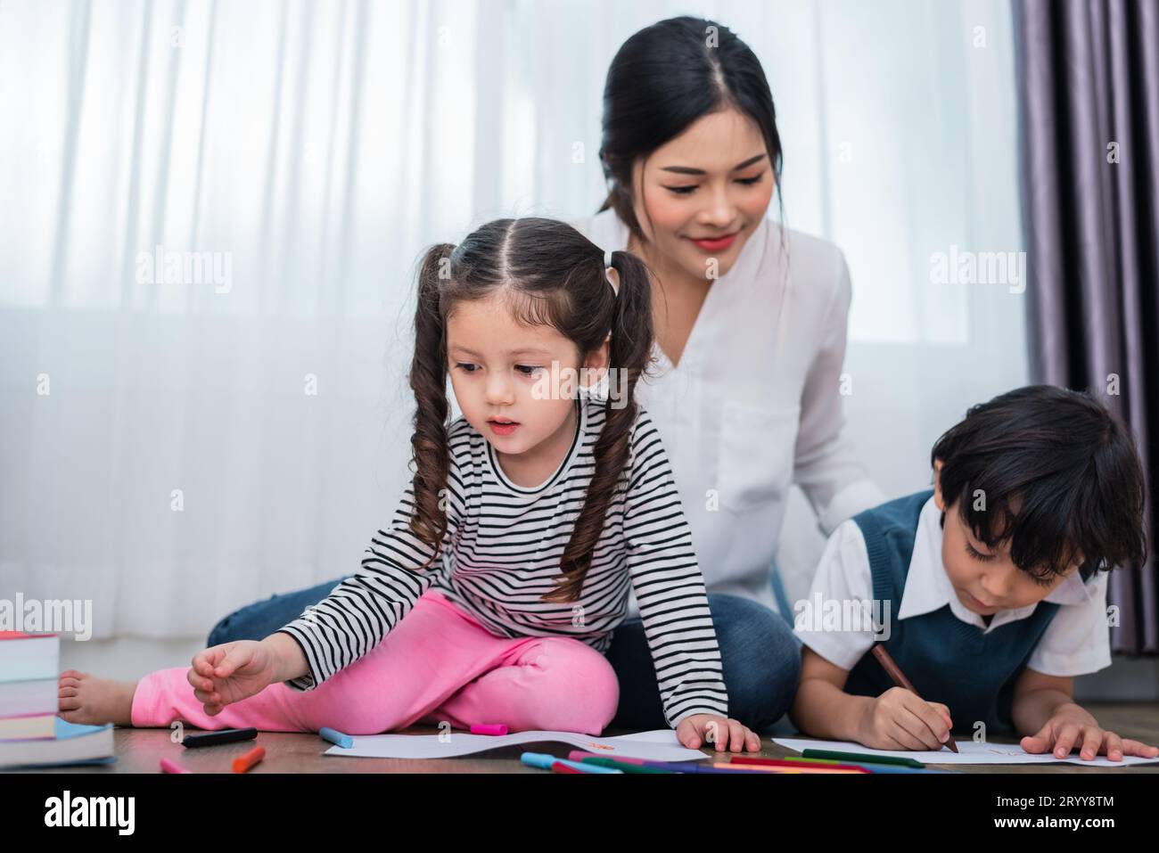 Mère enseignant aux enfants en classe de dessin. Fille et fils peinture avec couleur de crayon coloré à la maison. Studen de formation des enseignants Banque D'Images