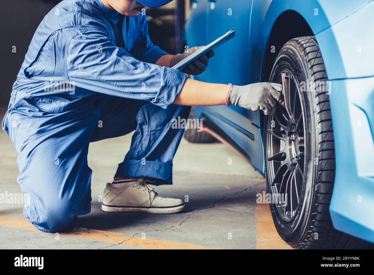 Technicien mécanicien automobile asiatique holding clipboard et contrôle de l'entretien de véhicules de la part de la demande du client dans l'ordre de réparation d'automobiles garage. Pneu roue rep Banque D'Images