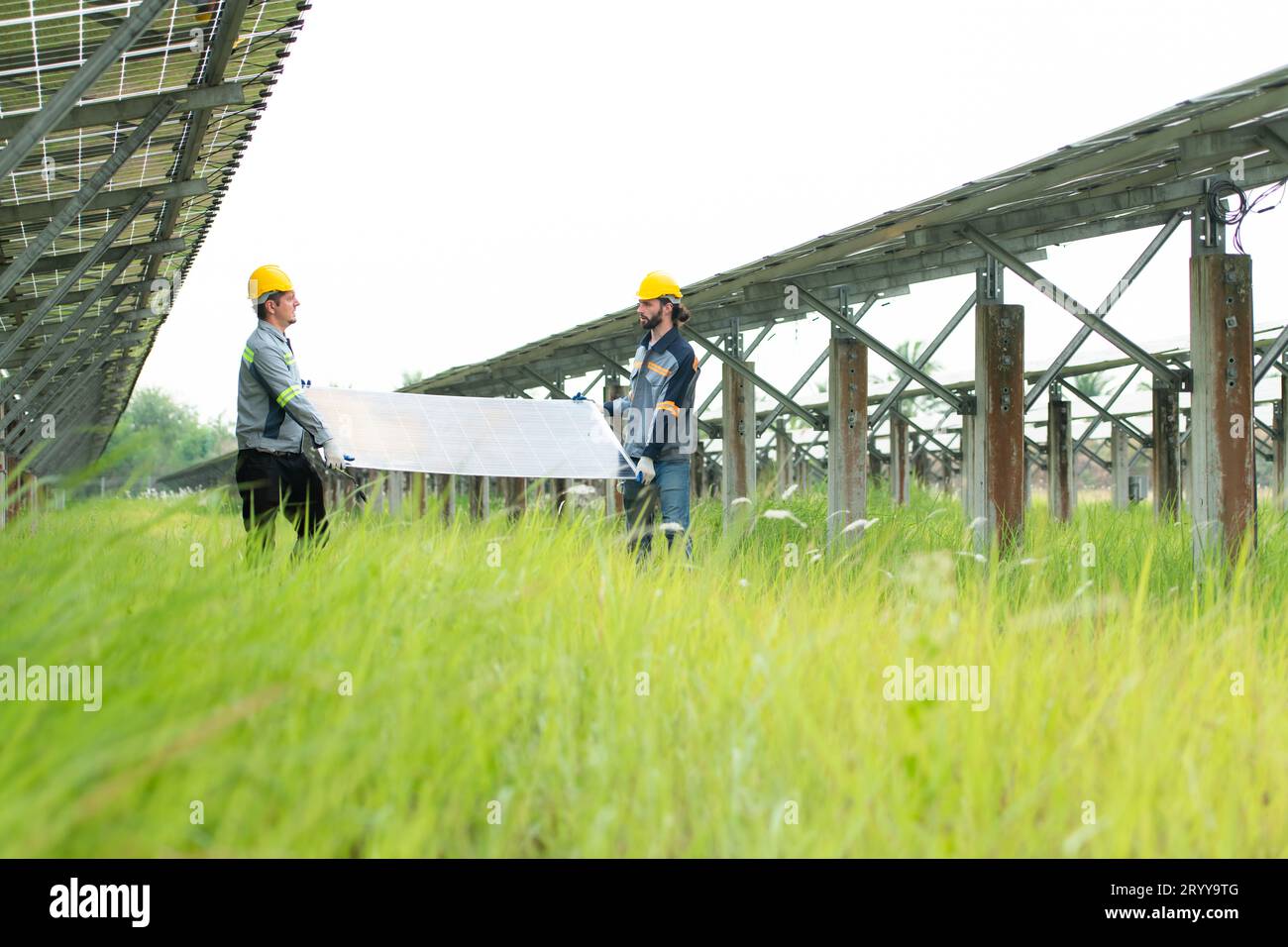 Ingénierie et technicien déchargeant des panneaux solaires réparés à installer sur les rangées de cellules solaires alignées sur des centaines de ca Banque D'Images