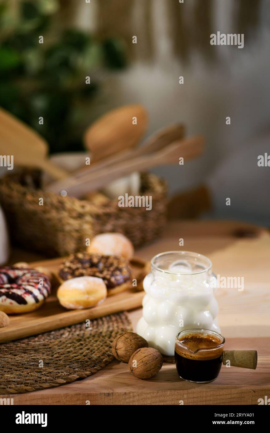Un plateau en bois peut contenir des beignets, des biscuits fourrés de chocolat et des biscuits de petite taille. Derrière, les noix reposent sur un tissu blanc, avec des ustensiles en bois dans une mèche Banque D'Images