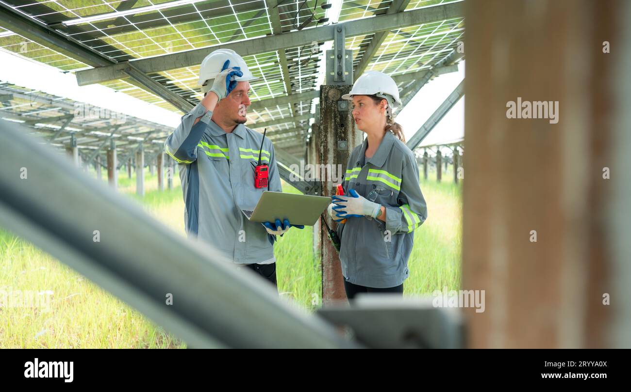 Une équipe d'ingénieurs électriciens inspecte et entretient des panneaux solaires sur un site de panneaux solaires au milieu d'une centaine d'acres Banque D'Images