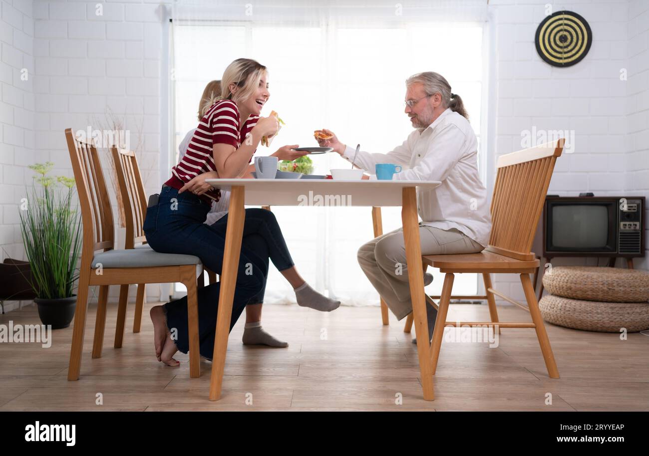 Le père, la mère et la fille sont ravis de dîner ensemble à la table familiale. Banque D'Images