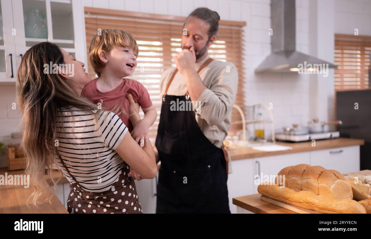 Maman et papa dans la cuisine de la maison avec leurs petits enfants. Amusez-vous bien à préparer le dîner ensemble. Banque D'Images