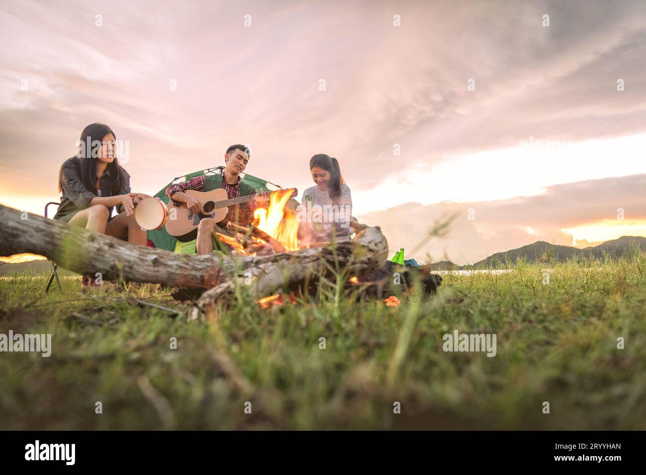 Groupe de voyageurs campant et faisant pique-nique et jouant de la musique ensemble. Fond de montagne et de lac. Les gens et le style de vie. OUTD Banque D'Images