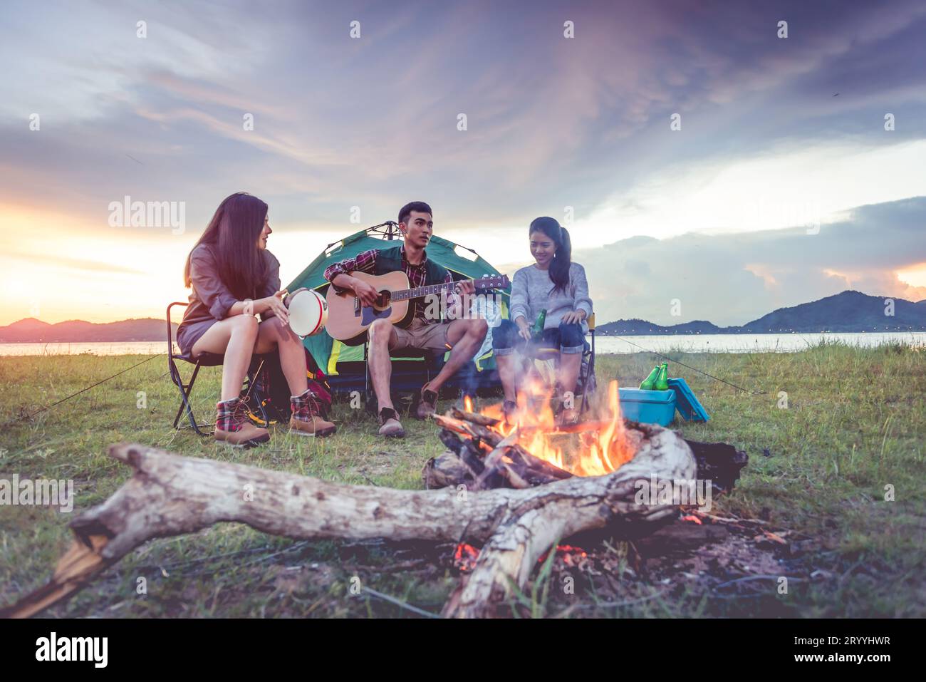 Groupe de voyageurs campant et faisant pique-nique et jouant de la musique ensemble. Fond de montagne et de lac. Les gens et le style de vie. OUTD Banque D'Images