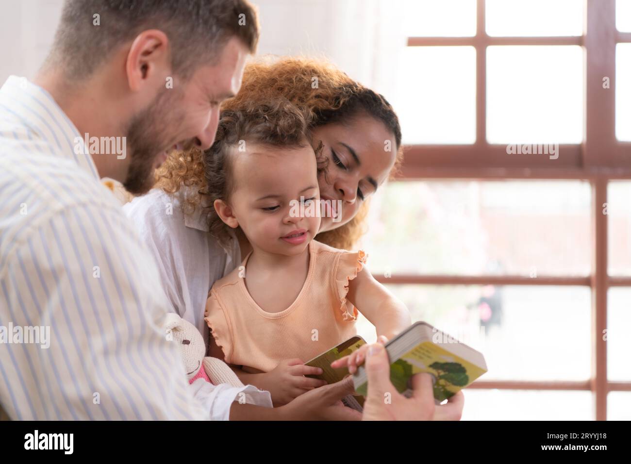 Parents et enfants se détendent dans le salon de la maison. Regardez bébé jouer joyeusement avec son jouet préféré. Banque D'Images