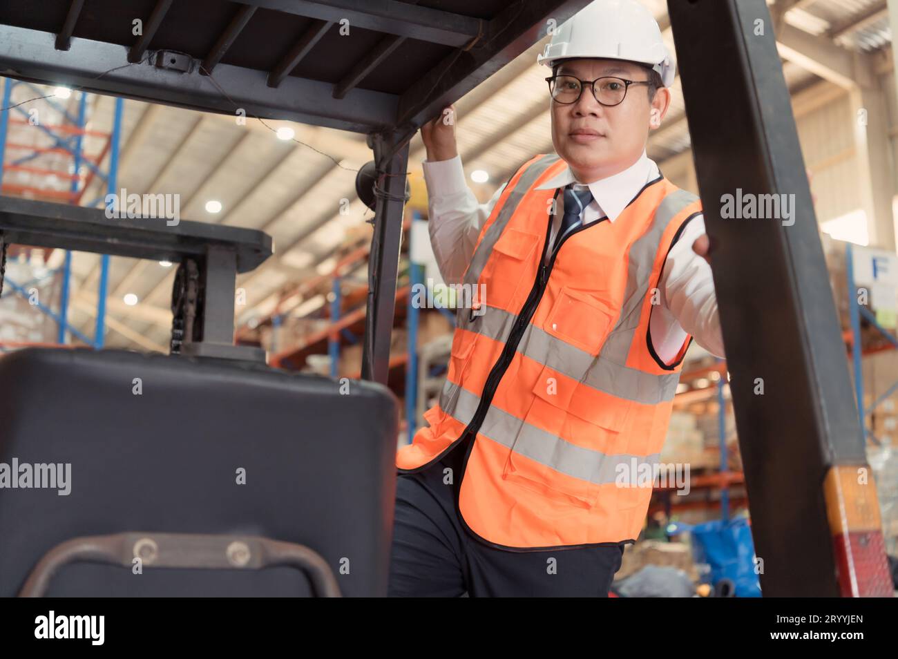 Le gestionnaire d'entrepôt examine l'équipement utilisé pour déplacer les marchandises dans l'entrepôt et fait l'essai routier d'un chariot élévateur. Banque D'Images