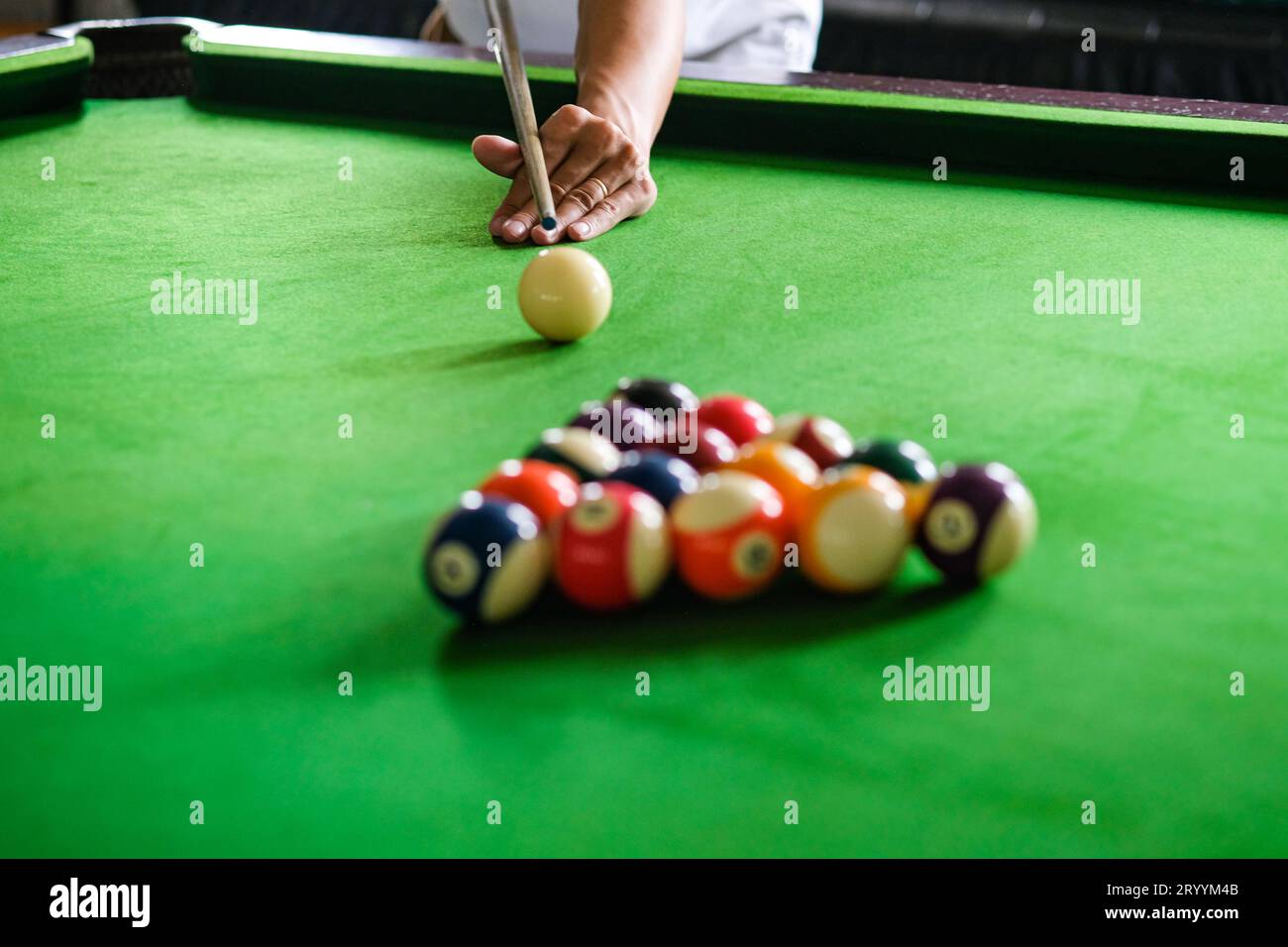 La main de l'homme et le bras de Cue jouant au jeu de snooker ou se préparant à tirer des balles de billard sur une table de billard verte. Snooker coloré Banque D'Images