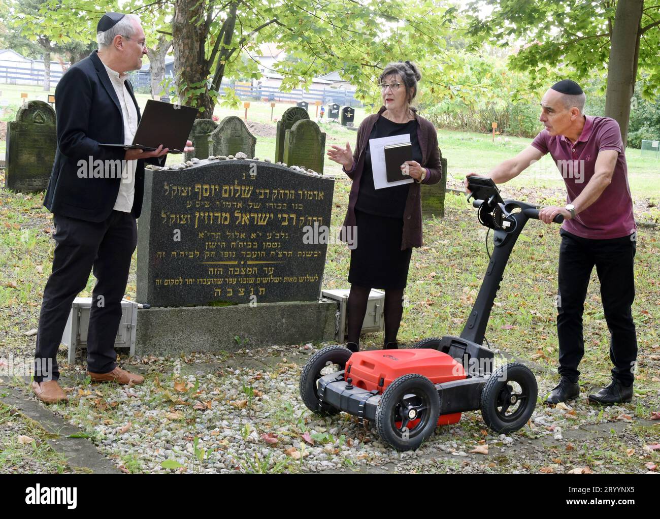 PRODUCTION - 29 septembre 2023, Saxe, Leipzig : au Nouveau cimetière juif, Ralf Thiele (r), professeur d'ingénierie géotechnique à l'Université des sciences appliquées et des arts (HTWK), étudie le lieu de repos juif du site Johannistal, qui a été béni en 1928, avec un radar pénétrant dans le sol, avec le juif Leipzig de 75 ans ETA Zachäus et Ronald Scherzer-Heidenberger, architecte. Avec les mesures de la roue au sol, les scientifiques de l'université soutiennent la communauté religieuse juive dans la recherche, l'entretien et l'agrandissement du premier cimetière juif de la ville. Banque D'Images