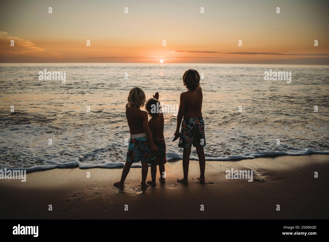 Les enfants debout à la plage regardant un magnifique coucher de soleil en Espagne Banque D'Images