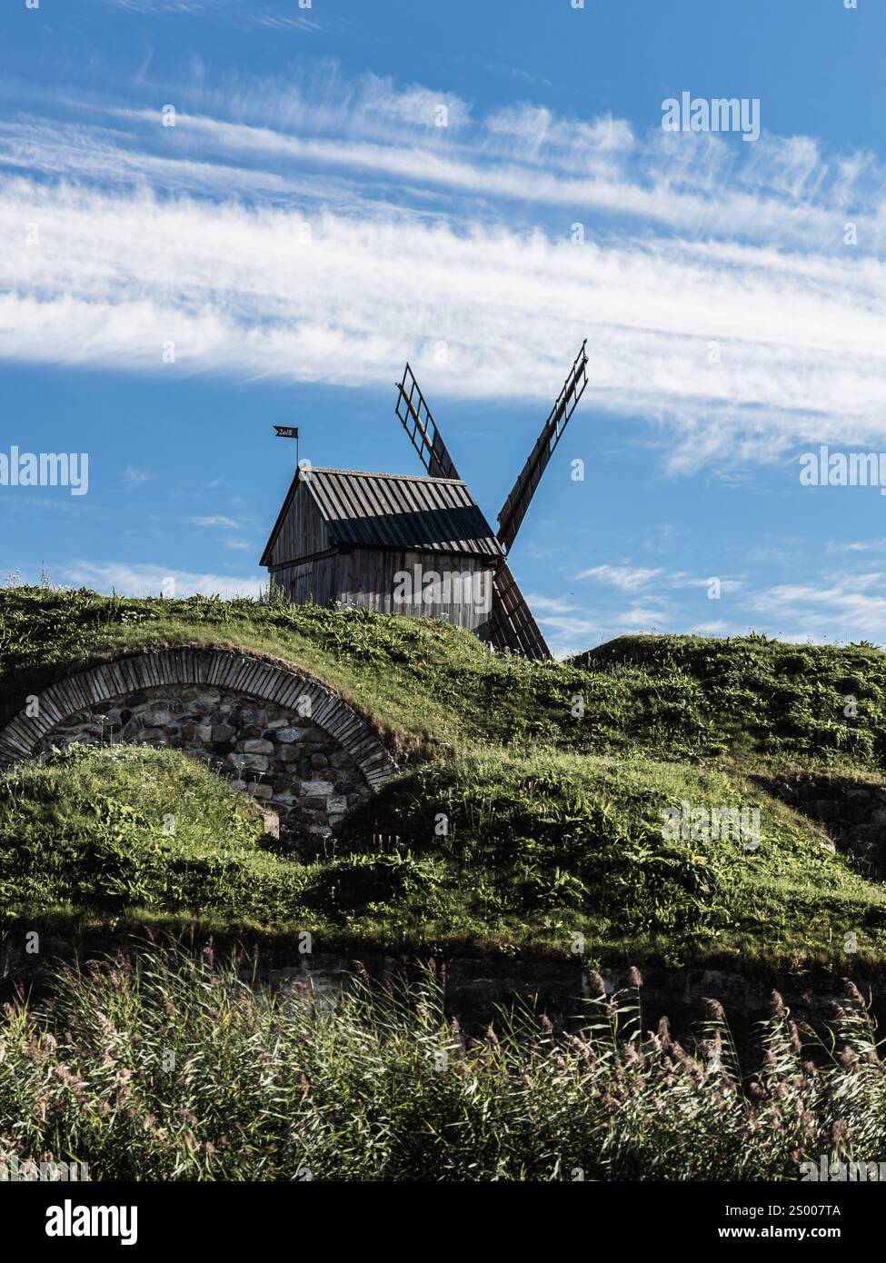 Moulin à vent en bois sur une élévation de mur de pierre Banque D'Images