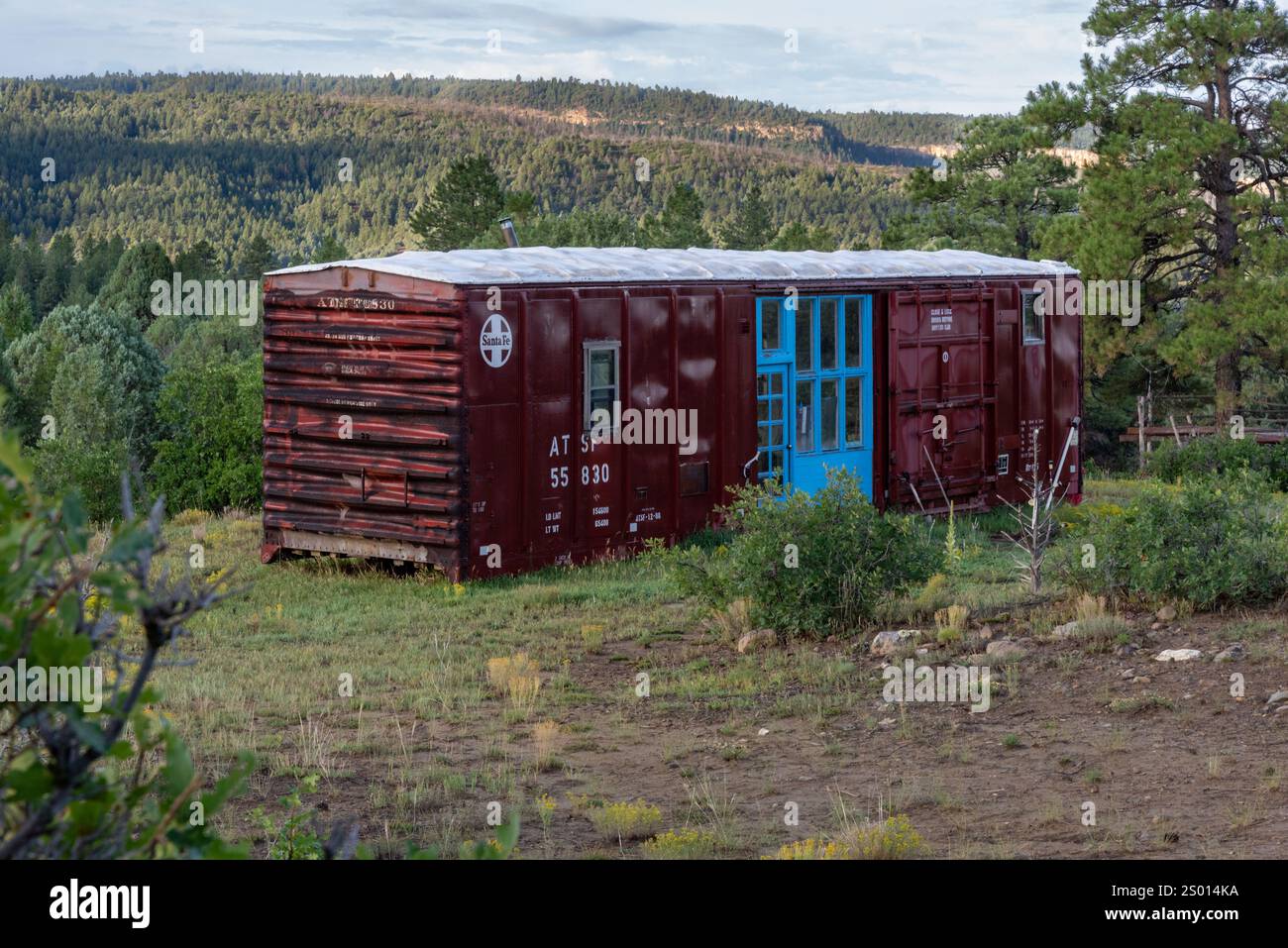 Santa Fe Railroad box car converti en espace de vie avec une grande entrée en bois de couleur turquoise avec de grandes fenêtres dans la région éloignée, Nouveau-Mexique États-Unis Banque D'Images