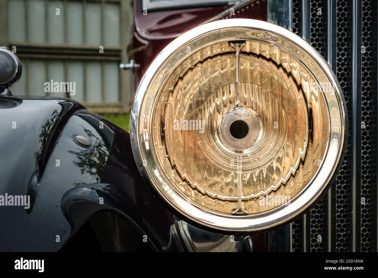 Gros plan et mise au point sélective d'un grand phare lumineux, d'une grande courbe de l'aile latérale et d'une calandre avant emblématique du radiateur de voiture d'avant-guerre vintage. Voiture classique, design et métal poli. Style automobile d'une époque révolue. Banque D'Images