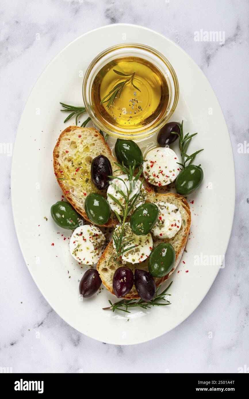 Une assiette avec une collation, pain ciabatta avec fromage et olives, huile d'olive, épices et herbes, vue de dessus, pas de gens Banque D'Images