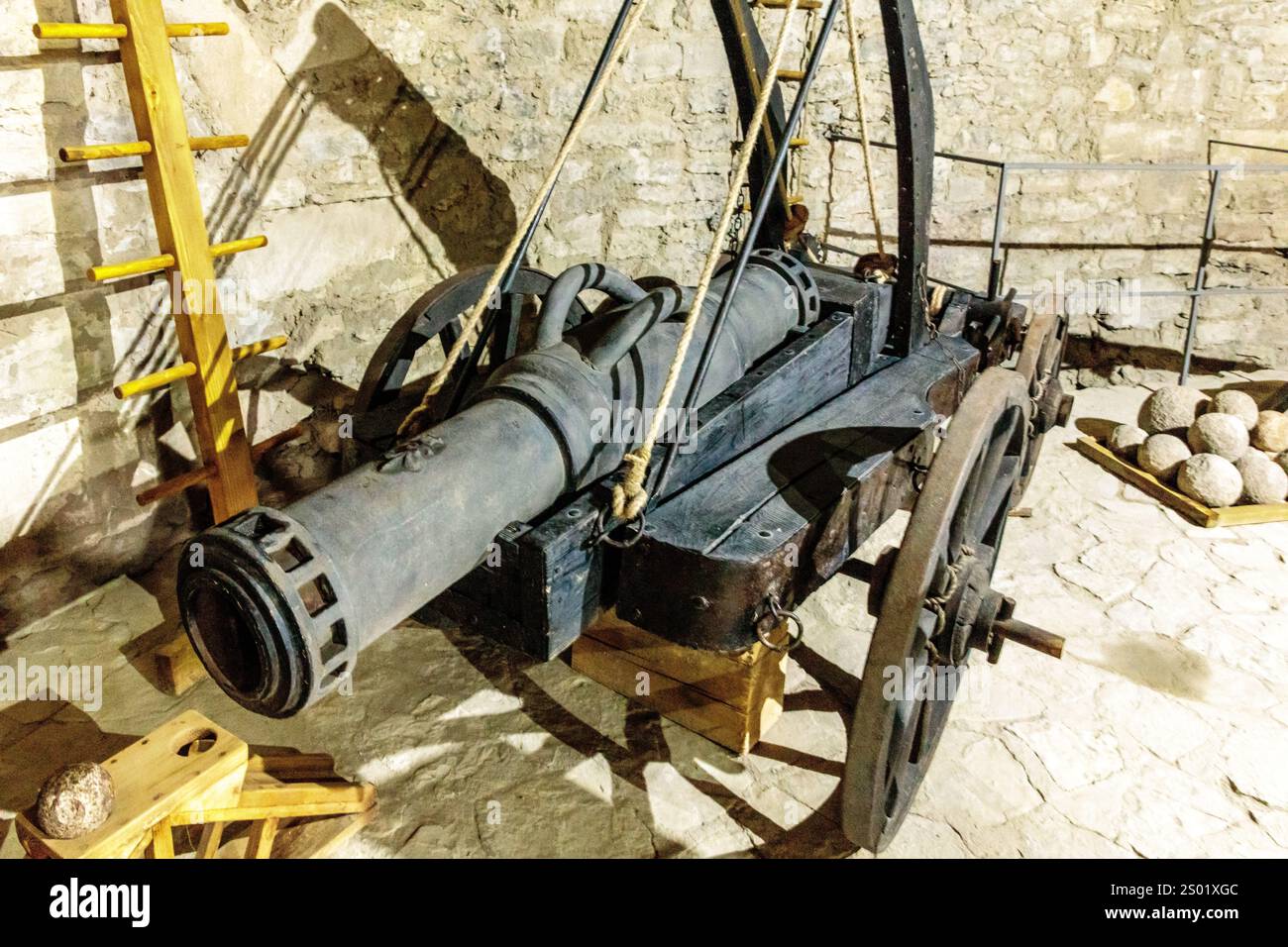 Un canon est assis dans une pièce avec une échelle et un tas de rochers. Le canon est vieux et rouillé, et il semble être un artefact historique. La scène en est une Banque D'Images