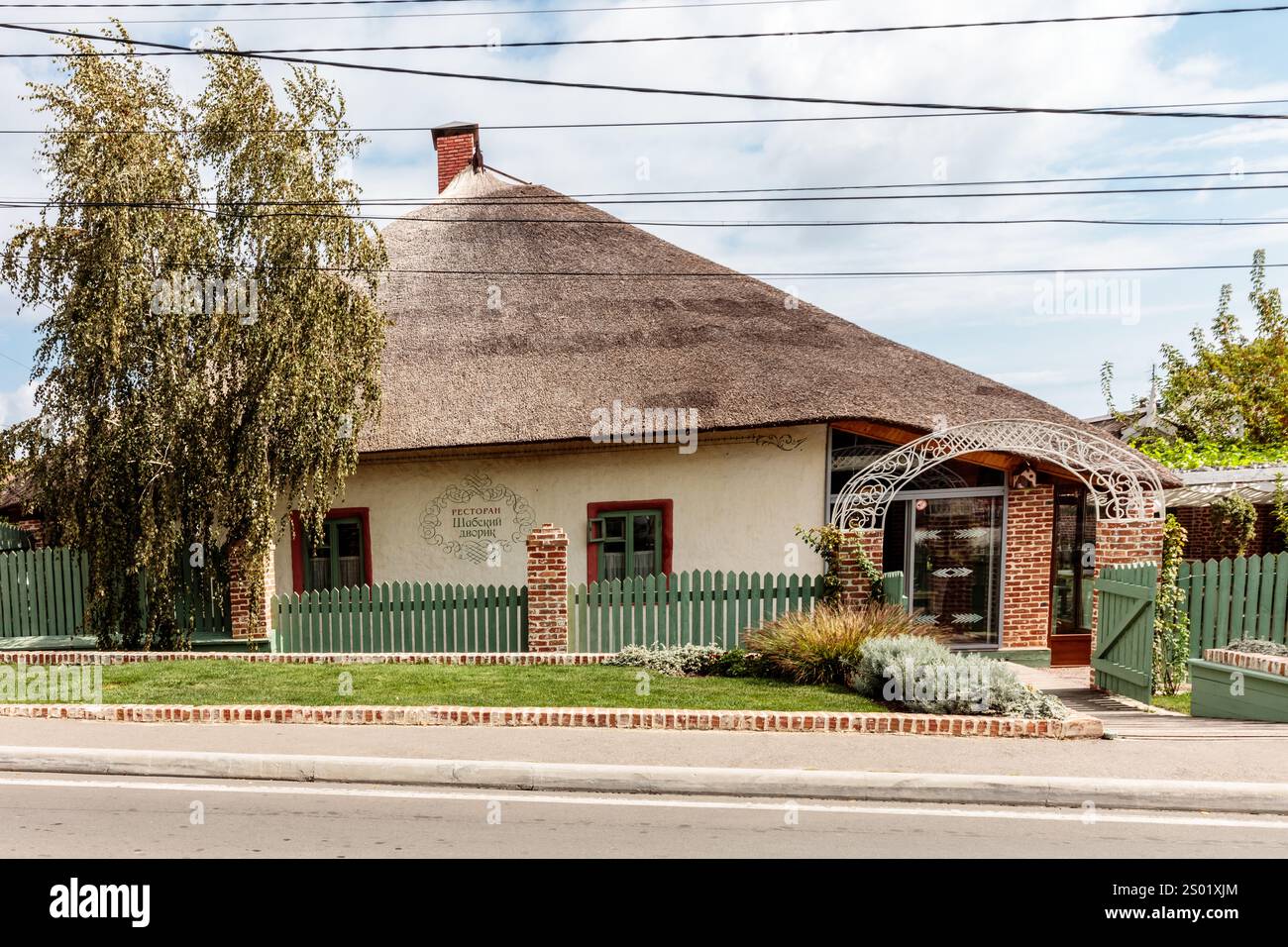 Une petite maison avec une clôture verte et un toit vert. La maison est entourée d'un buisson vert Banque D'Images