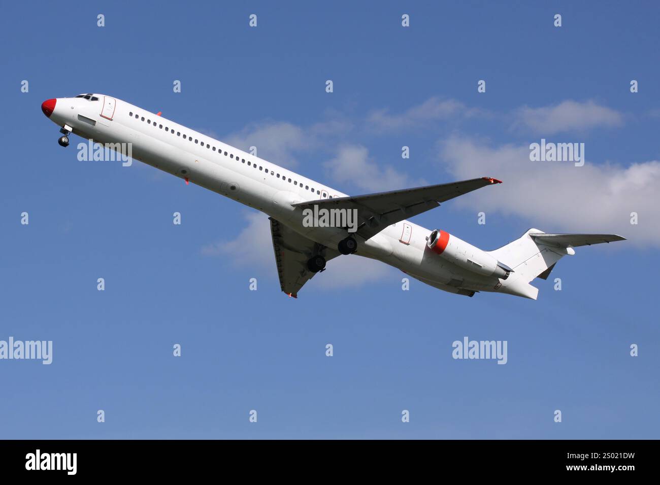 Avion de passagers blanc avec nez rouge décollant sur fond de ciel bleu clair Banque D'Images