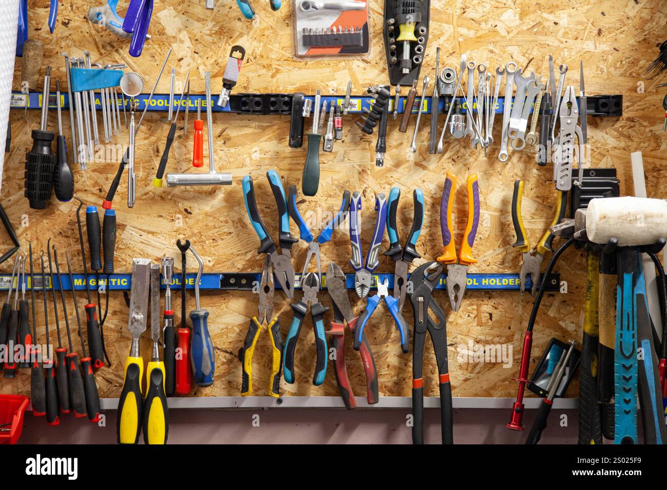 Fond avec mur avec outils de toutes tailles, tournevis, pinces et autres outils spéciaux dans le garage Banque D'Images