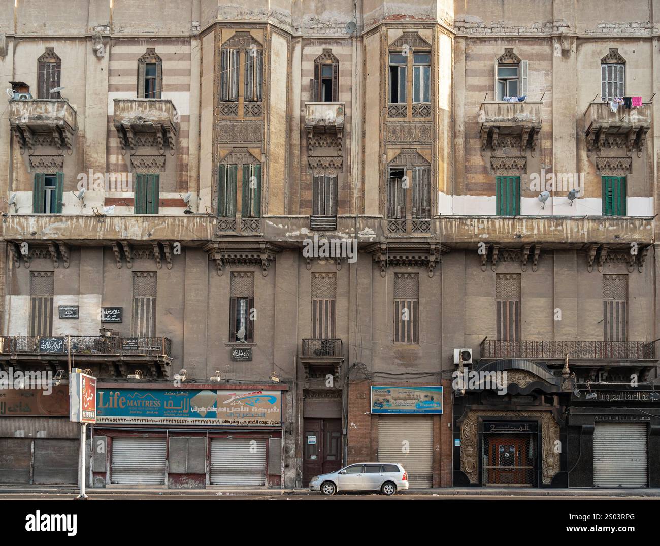 Un ancien bâtiment résidentiel avec des balcons ornés et des façades altérées à Alexandrie, en Égypte, reflétant l'architecture historique de la ville. Banque D'Images