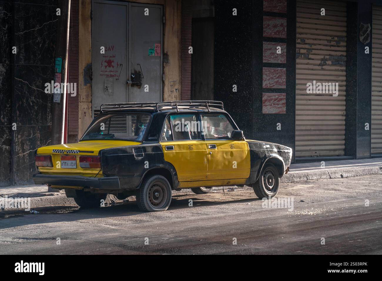Un taxi noir et jaune vintage garé dans une rue d'Alexandrie, en Égypte, présente le style de transport local et l'atmosphère urbaine de la ville. Banque D'Images