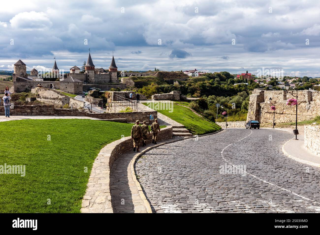 Un groupe de soldats descend une rue pavée devant un château. Le ciel est nuageux et l'atmosphère est paisible Banque D'Images