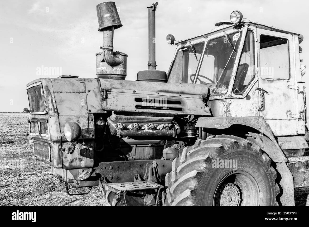 Un vieux tracteur avec un filtre noir et blanc. Le tracteur est stationné dans un champ Banque D'Images