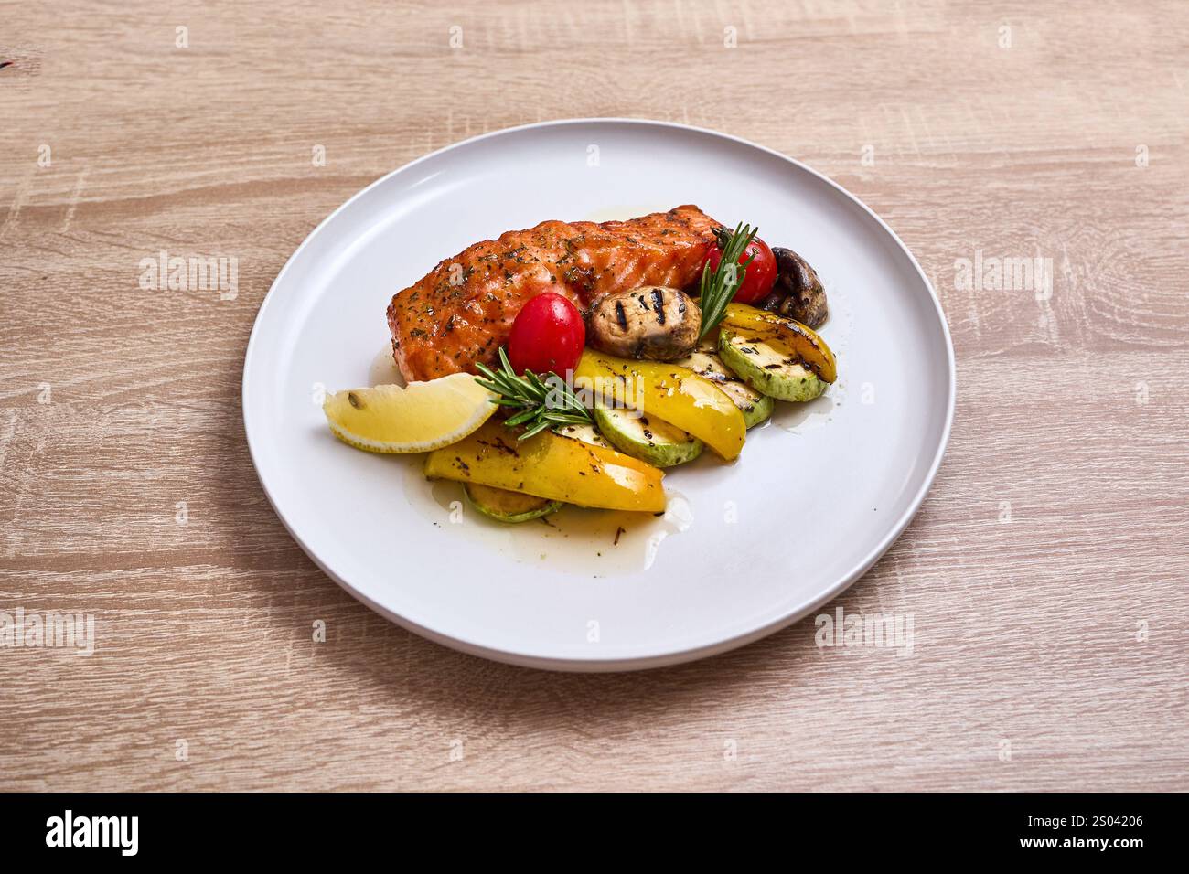 Filet de saumon grillé servi avec des légumes rôtis et un coin de citron. Banque D'Images