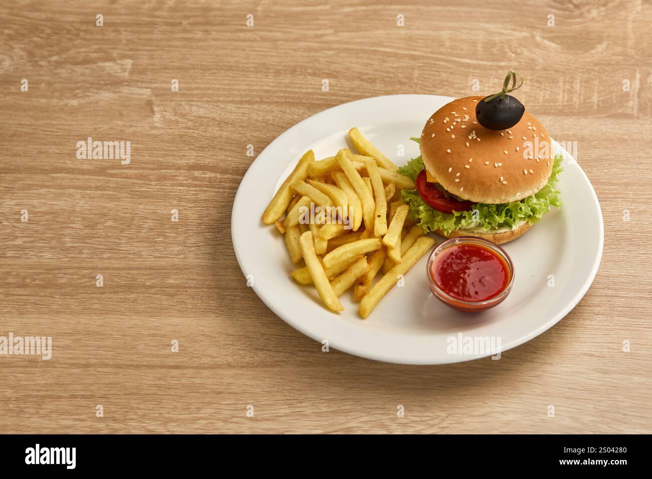 Un savoureux cheeseburger avec frites croustillantes et sauce, servi sur une assiette blanche. Banque D'Images