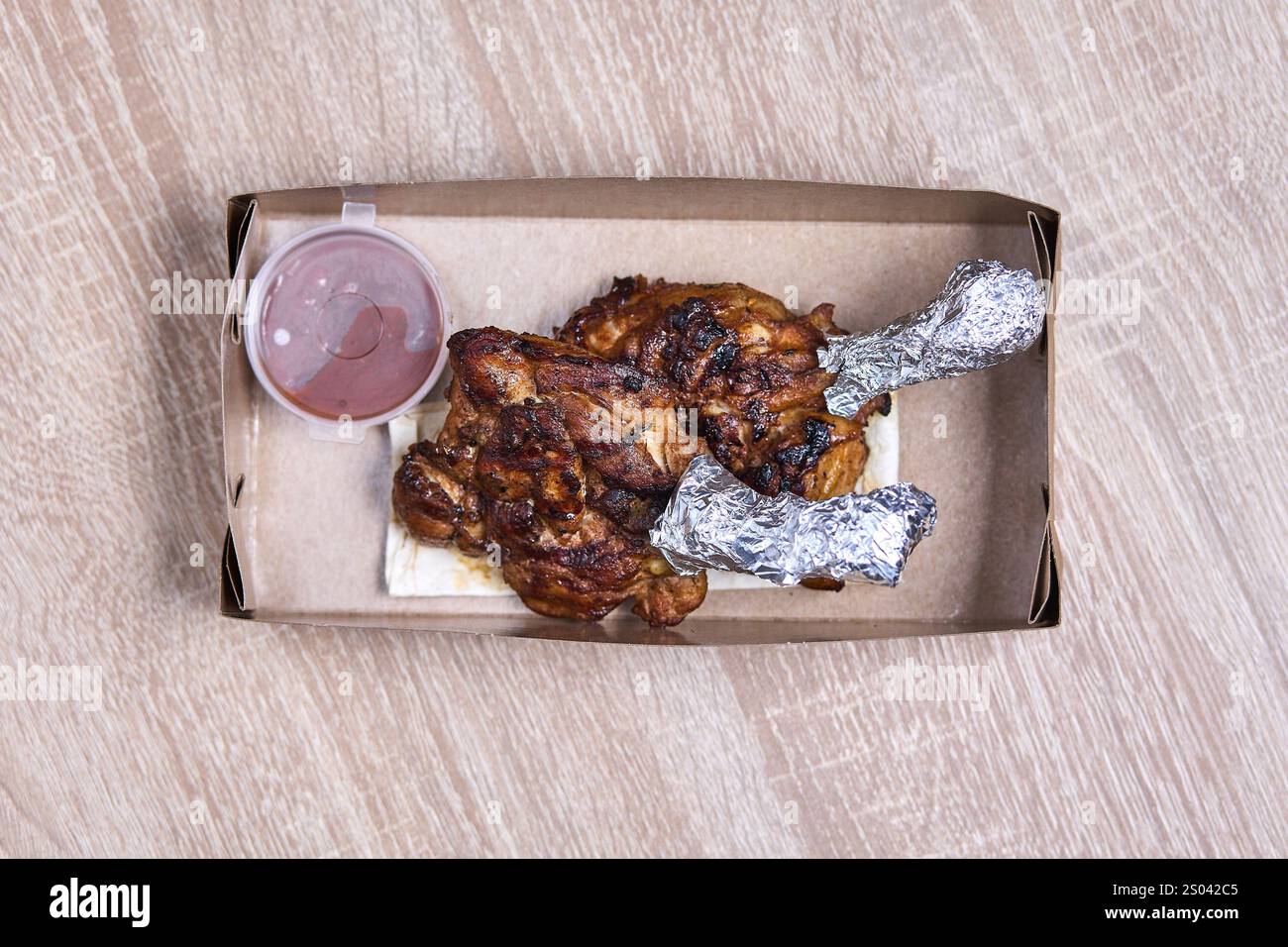 Deux cuisses de poulet grillées avec sauce dans une boîte en carton à emporter. Banque D'Images Deux cuisses de poulet grillées avec sauce dans une boîte en carton à emporter. Banque D'Images