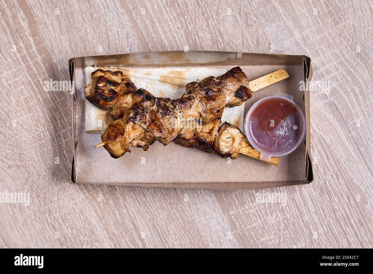 Deux brochettes de poulet grillé avec sauce dans une boîte en carton à emporter. Banque D'Images Deux brochettes de poulet grillé avec sauce dans une boîte en carton à emporter. Banque D'Images