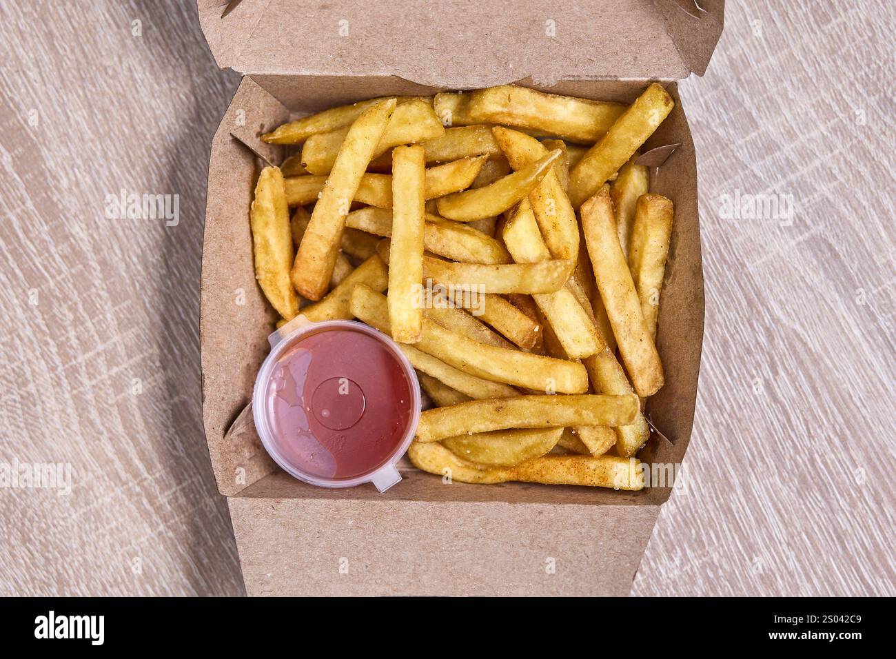 Frites dorées croustillantes servies avec ketchup dans une boîte en carton. Banque D'Images Frites dorées croustillantes servies avec ketchup dans une boîte en carton. Banque D'Images
