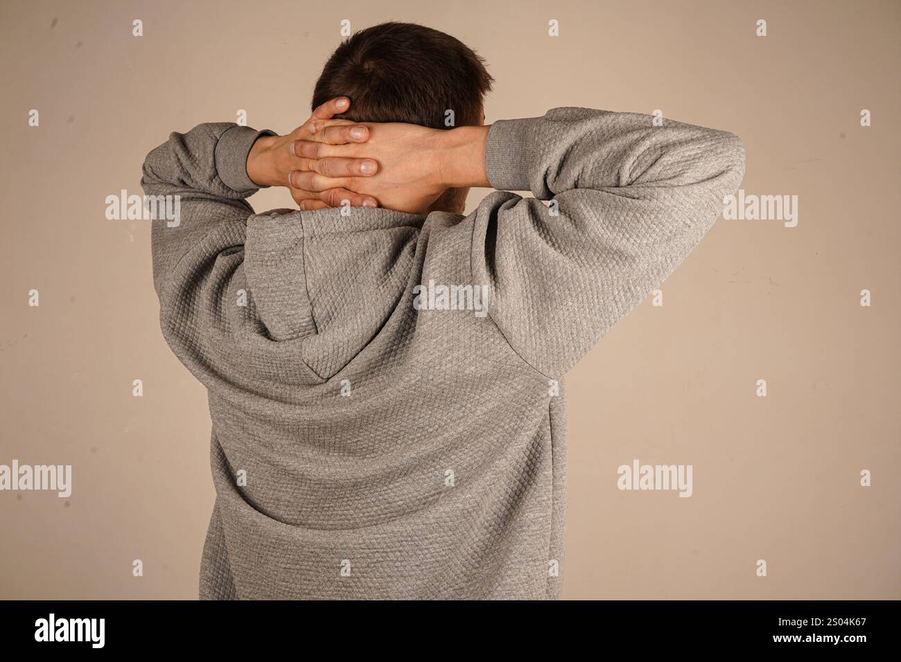 Mains sur l'arrière de la tête de l'homme. Détendu et étirant les bras et les mains derrière la tête et le cou de l'homme d'âge moyen portant un sweat à capuche sur fond isolé. Ha Banque D'Images