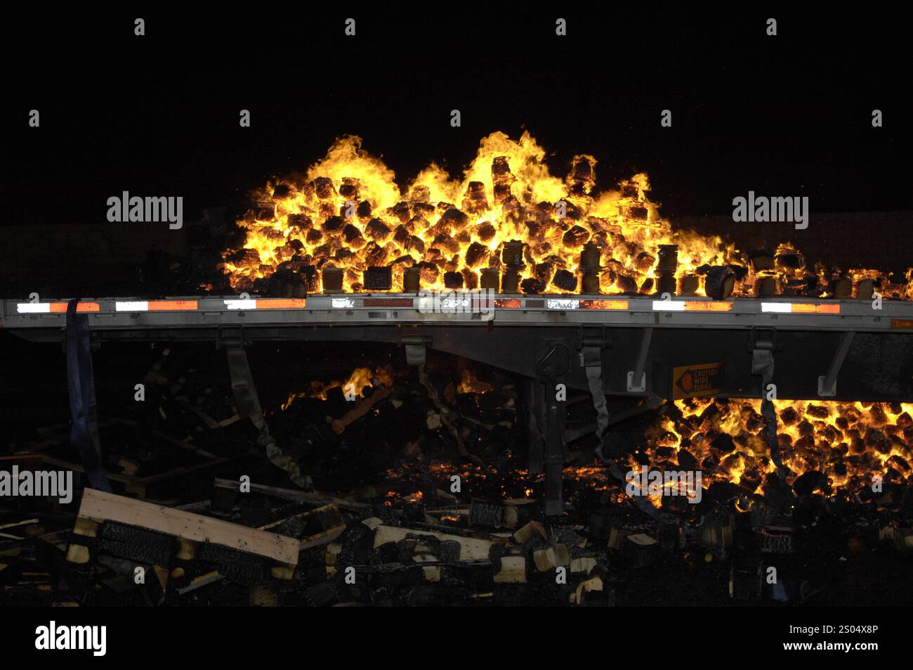 Braises brûlantes et incandescentes sur une remorque à plateau à la suite d'un incendie dans une cour de palettes à San Bernardino, en Californie Banque D'Images