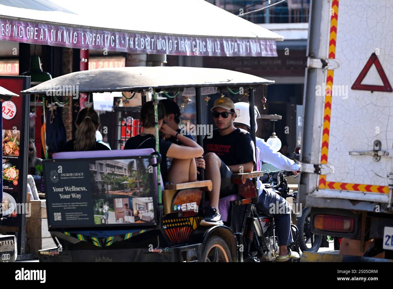 Un chauffeur de tuk tuk (taxi) part avec des touristes occidentaux sur Pub Street à Siem Reap, au Cambodge. Banque D'Images